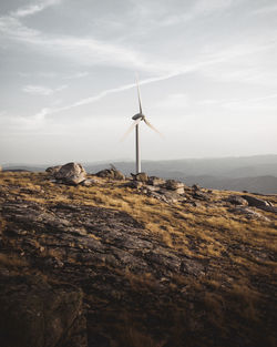 Wind turbine on mountain against sky