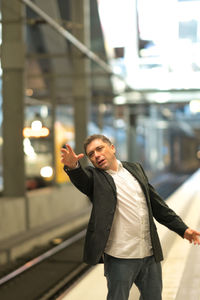 Thoughtful businessman gesturing at railroad station platform