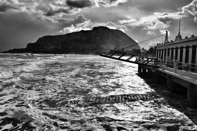 Pier on sea against cloudy sky