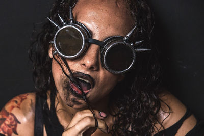 Portrait of funky woman wearing sunglasses against black background