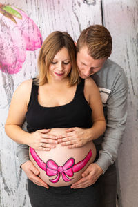 Man standing with pregnant woman against wall