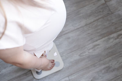 Pregnant woman with big belly measuring her pregnant weight standing on scales. selective focus