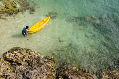 High angle view of man with yellow boat in sea