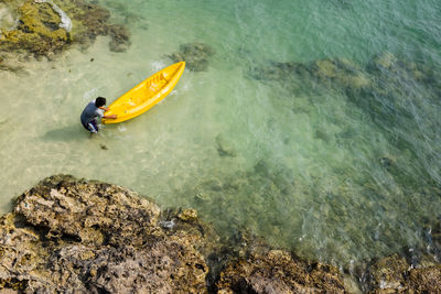 High angle view of person paragliding on rock by sea