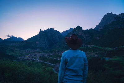 Rear view of man looking at mountains against sky