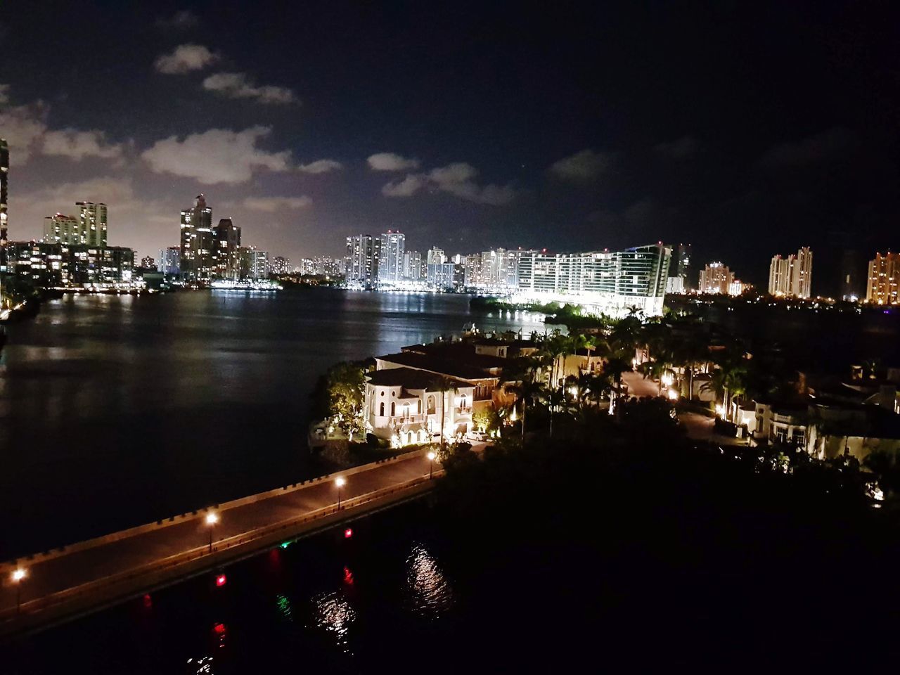 HIGH ANGLE VIEW OF ILLUMINATED BUILDINGS BY RIVER AGAINST SKY