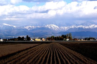 Scenic view of agricultural field by mountains against sky