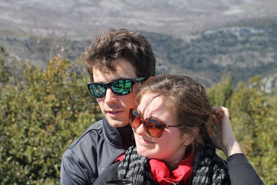 Portrait of happy young woman with sunglasses against mountain