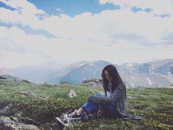  view of woman sitting on grass against mountain landscape