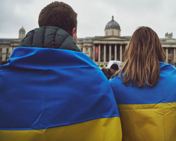 Rear view of couple draped in ukrainian flags