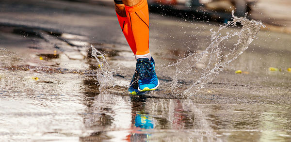 Low section of person running on puddle