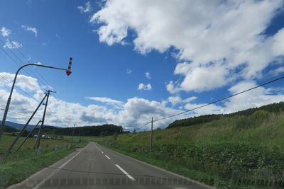 Road amidst field against sky