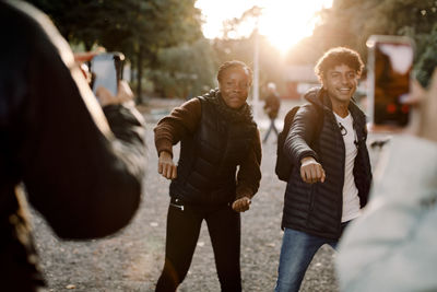 Friends filming teenage girl and boy dancing on street in city