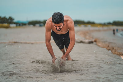 Full length of shirtless man on beach