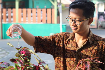 Portrait of young man wateringing plant