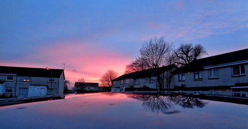 Illuminated houses against sky during sunset