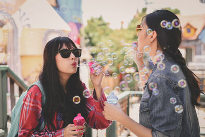 Friends blowing bubbles while standing in city