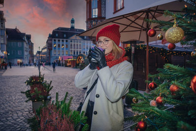 Rear view of woman standing by christmas tree