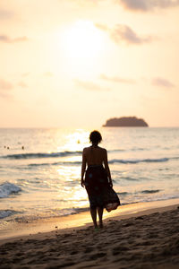 Rear view of man standing on beach during sunset