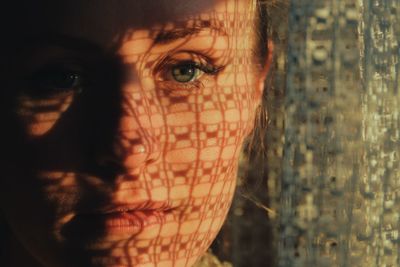 Close-up portrait of young woman by window at home