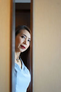 Portrait of woman looking through ajar door