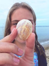 Close-up of young woman holding ice cream at beach