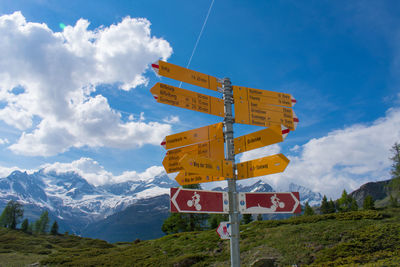 Low angle view of information sign against sky in mountains swiss alps with snowy mountains.