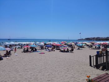 People at beach against clear blue sky