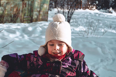 Happy child sits on tubing in the yard around the house. winter activities for children