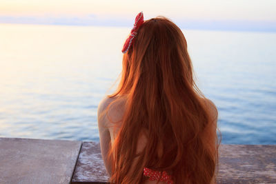 Rear view of woman by sea against sky