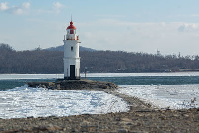 Lighthouse by sea against sky