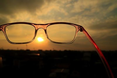 Close-up of silhouette eyeglasses against sky at sunset