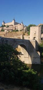 Arch bridge over river against buildings