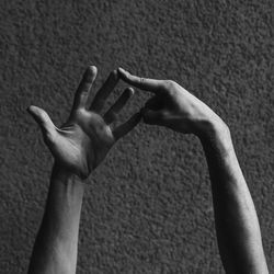 Cropped hands of man gesturing against wall