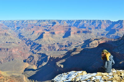 Rear view of woman standing on rock against sky