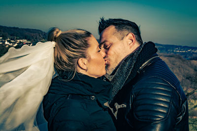 Midsection of couple kissing outdoors