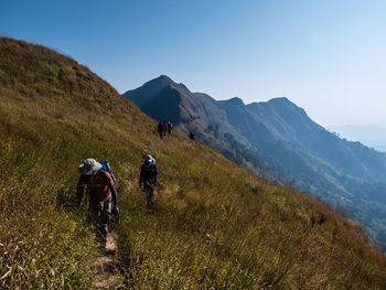 People walking on mountain against sky