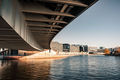 Bridge over river by buildings against sky