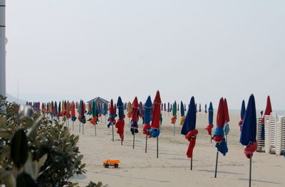 Closed canopies on beach against clear sky
