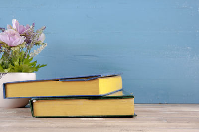 Flower vase on table against blue wall