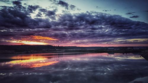 Scenic view of lake against dramatic sky during sunset