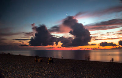 Silhouette people on beach against sky during sunset