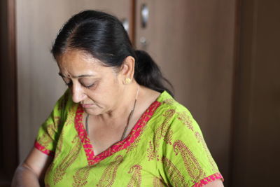 Close-up of woman looking down against door at home