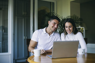 Portrait of smiling young man using phone on table