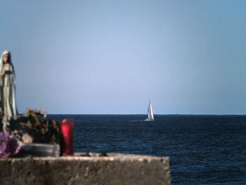 Sailboat sailing on sea against clear sky