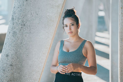 Portrait of young woman standing against wall