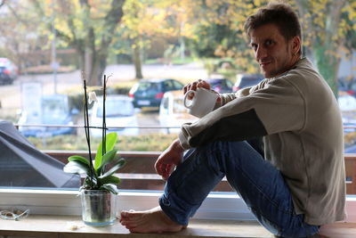 Portrait of man drinking coffee while sitting at window