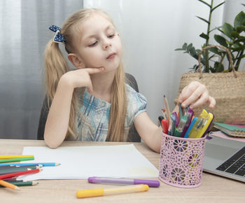 Girl choosing pen on table
