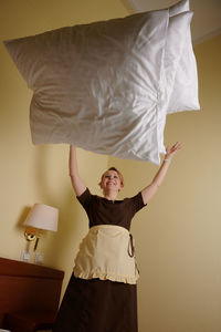 Rear view of young woman standing on bed at home