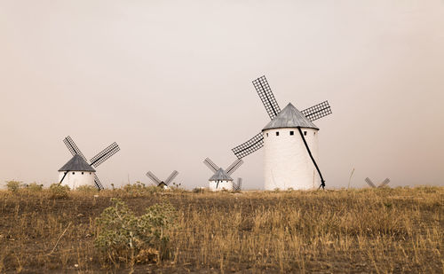 Spanish traditional white windmill on field against clear sky